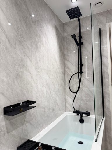 White bath with black matte overhead rain shower and glass shower screen fitted by bathroom specialists in Kent