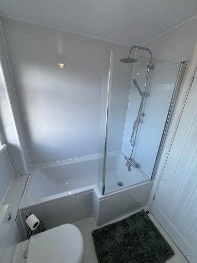 L-shaped shower bath with chrome thermostatic rain shower and glass screen fitted by bathroom installers in Kent