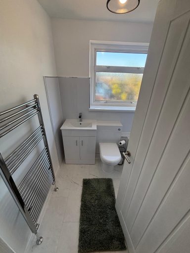 White bathroom with vanity unit, close-coupled WC and chrome heated towel rail  by bathroom fitters in Maidstone Kent